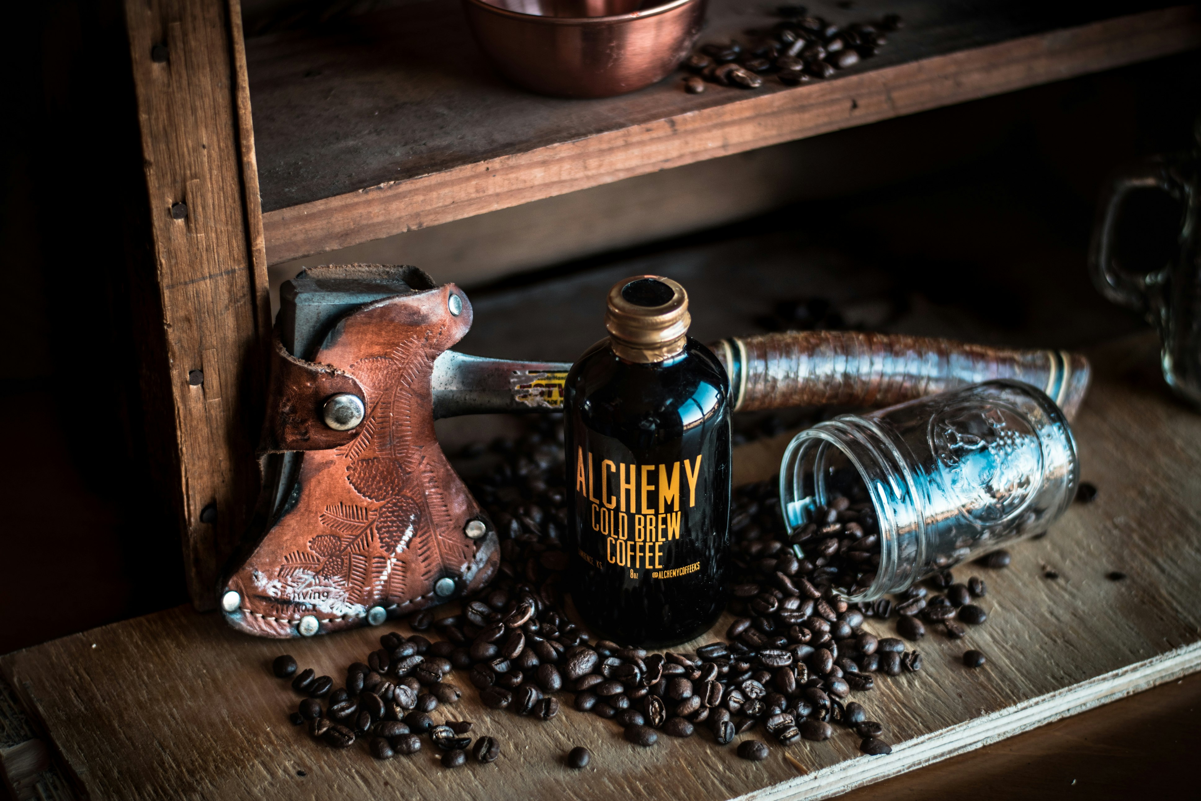 alchemy cold brew coffee bottle near the brown hatchet on brown wooden rack